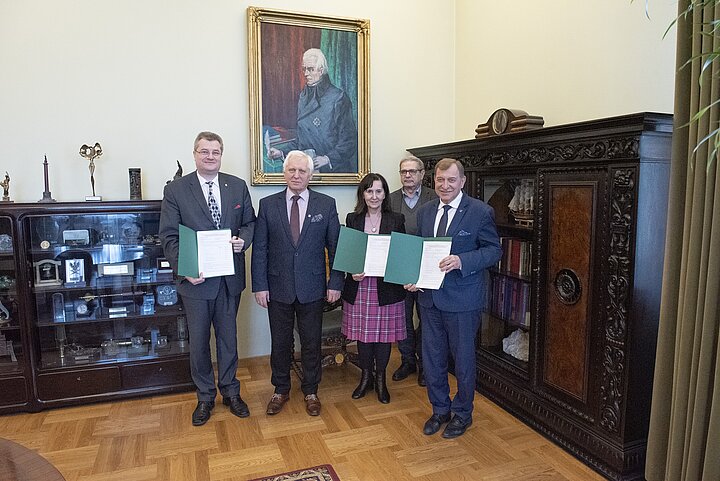 Cztery osoby stoją na tle portretu St. Staszica i prezentuja tresc porozumienia