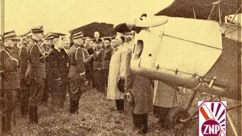 Historyczne zdjęcie przedstawiające grupę umundurowanych osób stojących w szyku obok samolotu. Widoczny fragment silnika i śmigła. W prawym dolnym rogu logo ZNP