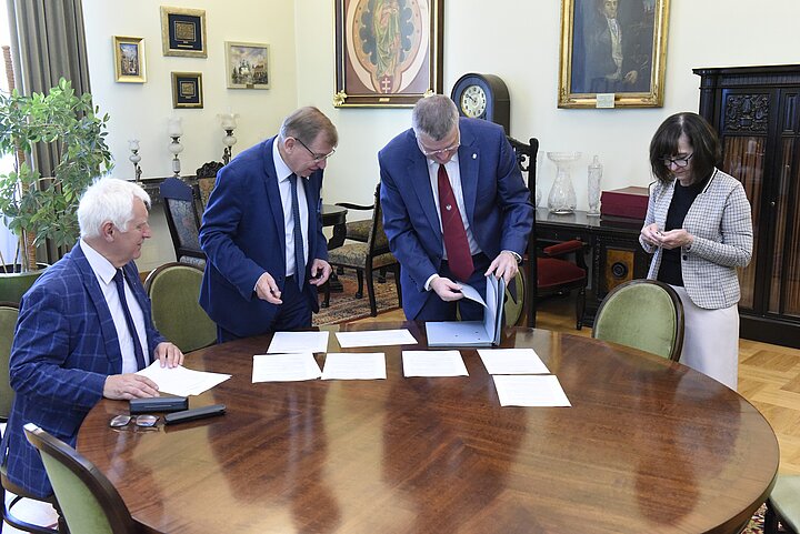 Grpa czterech osób debatuje nad dokumentem,podpisanie dokumentu i usmiechy