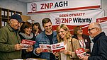 Grupa zadowolonych zwiazkowców ogląda ulotki z logotypem ZNP i usmiechajasię jak idioci