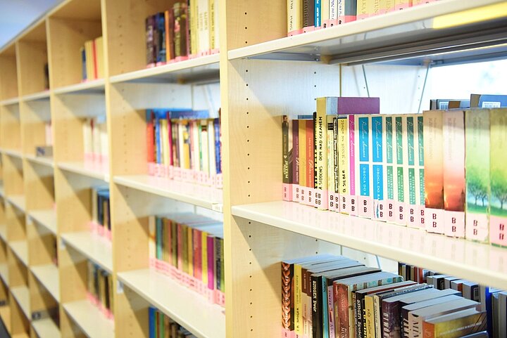 Duży rząd regałów z książkami, po prawej stronie fotele i stolik