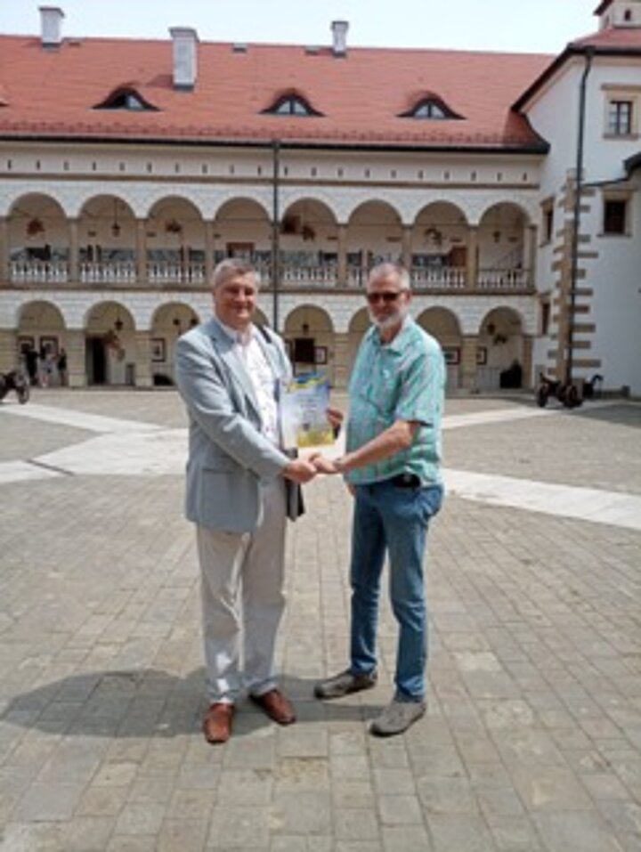 Mężczyźni stoją w grupie na tle Zamku w Niepołomicach